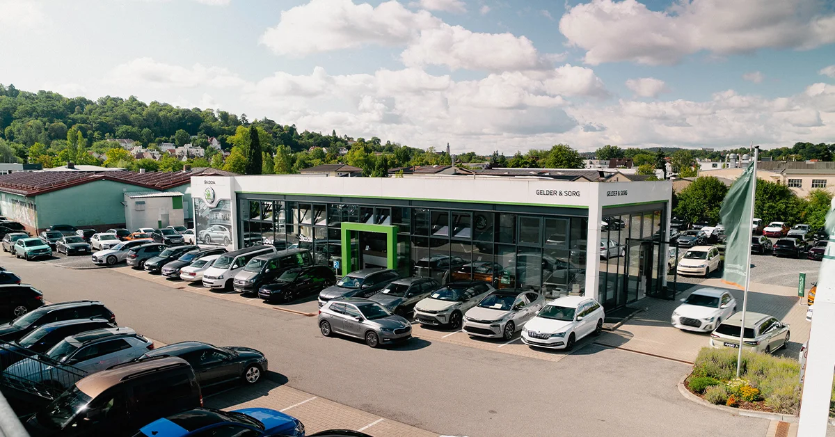Eine Aufnahme des Škoda Autohauses in Coburg, die das Gebäude und Škoda Fahrzeuge vor dem Gebäude, sowie die Einfahrt zeigt.