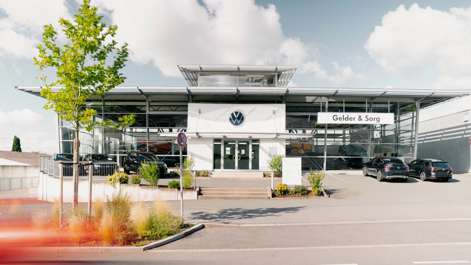 Eine Aufnahme des Volkswagen Autohauses in Coburg, dass den Haupteingang des Gebäudes und VW Fahrzeuge zeigt.