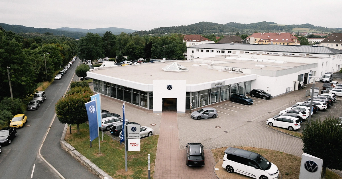 Eine Aufnahme des Volkswagen und Volkswagen Nutzfahrzeuge Autohauses in Eisenach, die das Gebäude und Volkswagen Fahrzeuge vor dem Gebäude, sowie die Einfahrt zeigt.