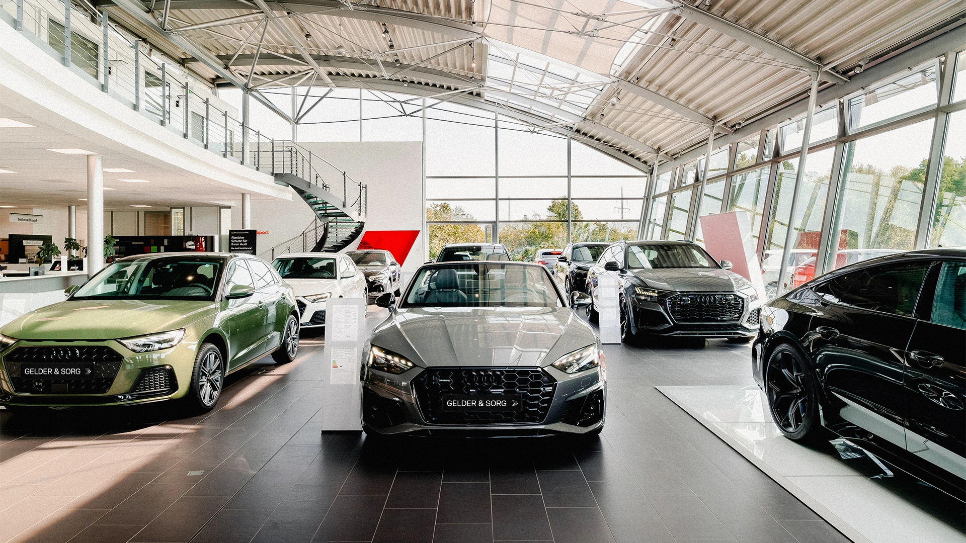 Gelder & Sorg Header Eine Innenaufnahme des Audi Autohauses in Haßfurt, die den Showroom und einige Audi Modelle zeigt.