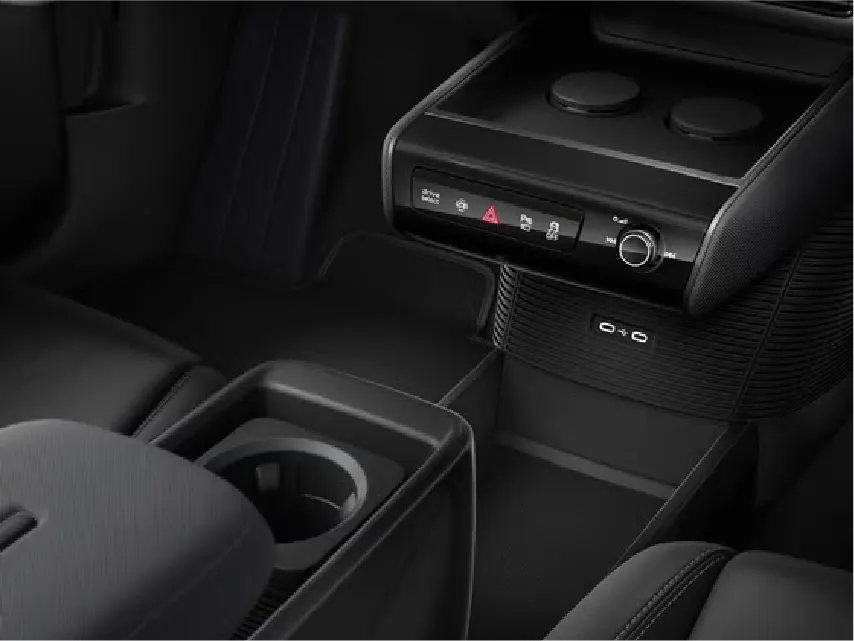 Nahaufnahme der schwarzen Mittelkonsole eines Audi mit Bedienfeld für Warnblinker und Fahrmodi, Drehregler, zwei USB-C-Anschlüssen sowie Becherhaltern und Ablagefächern im Fußraumbereich.