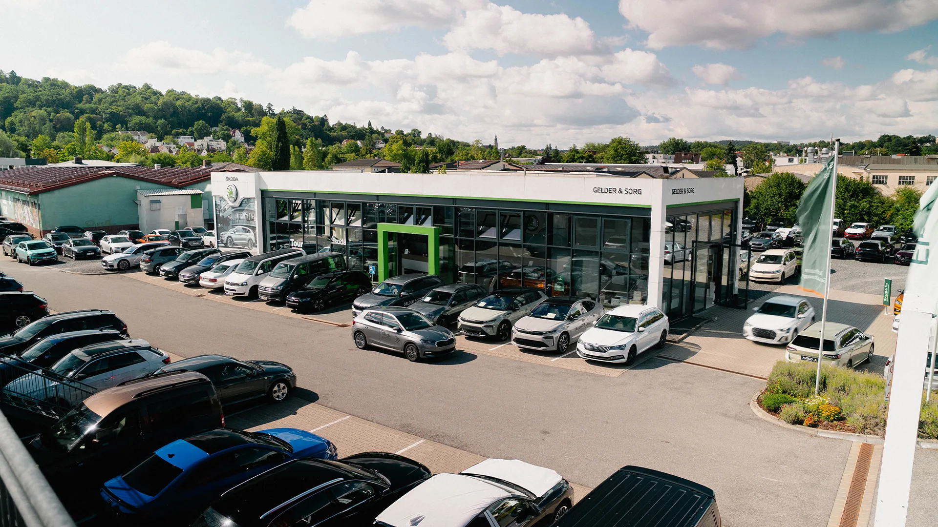 Eine Aufnahme des Škoda Autohauses in Coburg, dass den Haupteingang des Gebäudes, einen Teil des Hofes und Škoda Fahrzeuge zeigt.