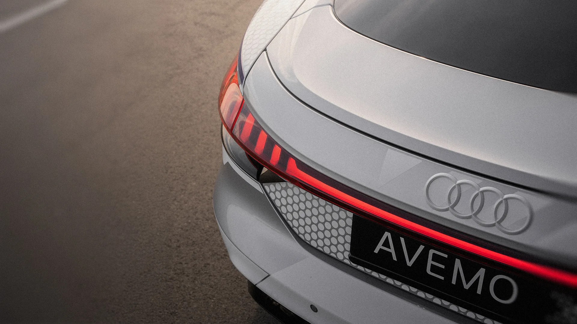 Eine Aufnahme eines Audi Hecks von schräg oben, die neben dem Fahrzeug einen Asphaltboden zeigt.