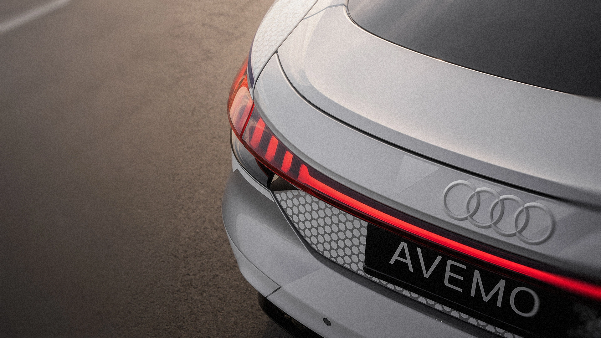 Eine Aufnahme eines Audi Hecks von schräg oben, die neben dem Fahrzeug einen Asphaltboden zeigt.