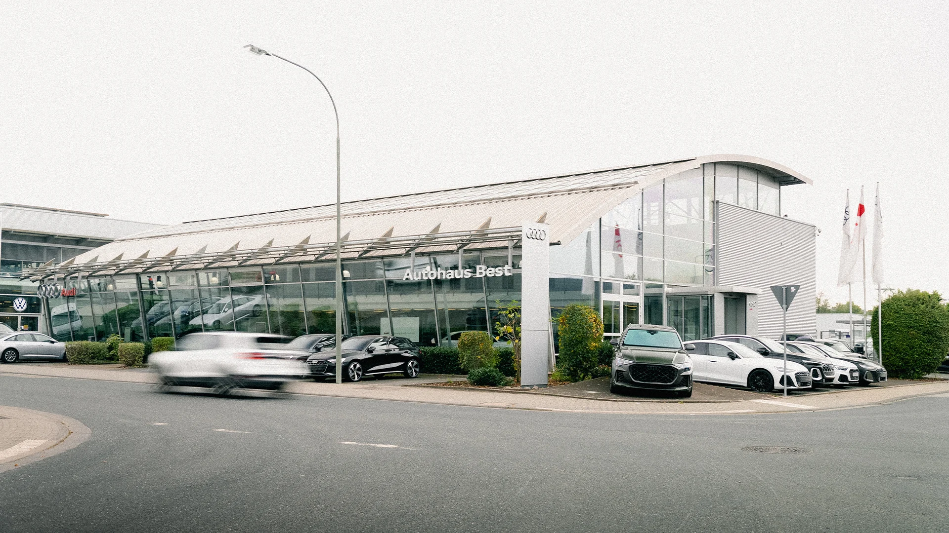 Eine Aufnahme des Audi Autohauses in Mühlheim am Main, dass die Gebäude und Audi Fahrzeuge vor dem Gebäude, sowie den Parkplatz zeigt.