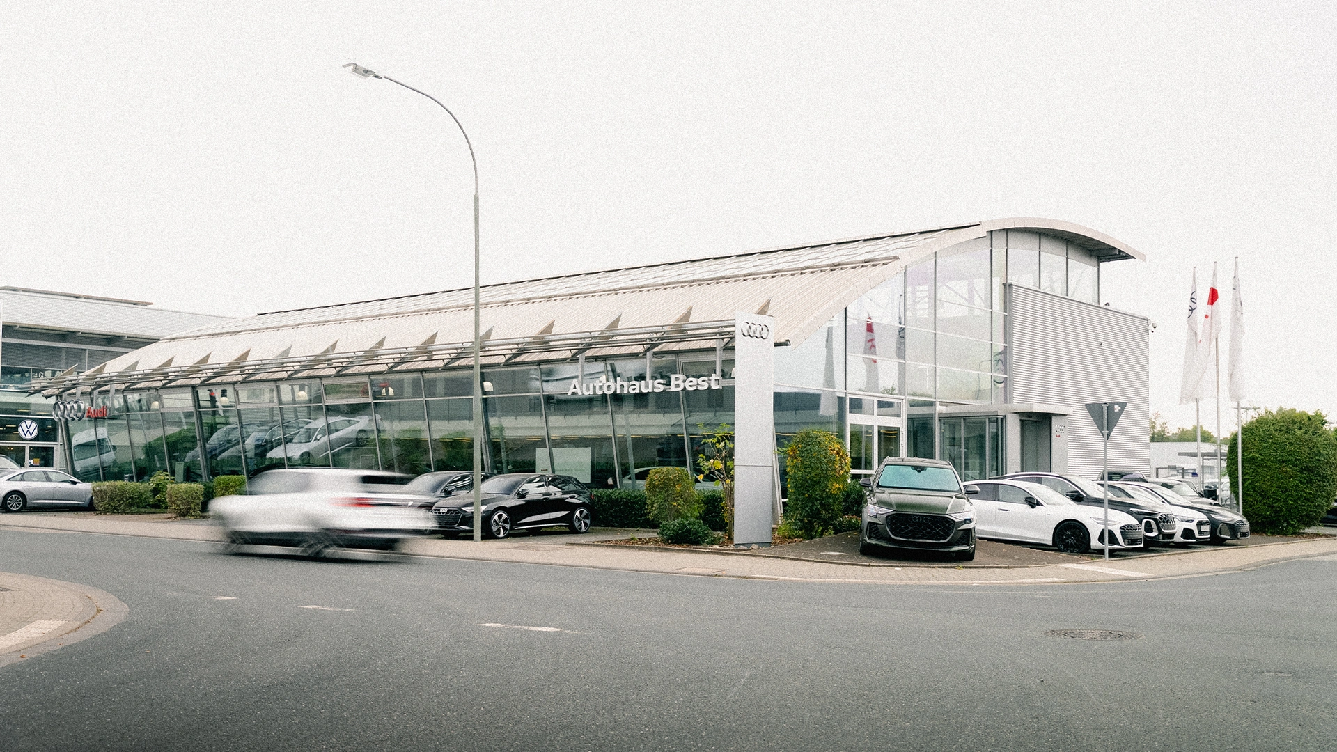 Audi Mühlheim am Main Header Eine Aufnahme des Audi Autohauses in Mühlheim am Main, dass die Gebäude und Audi Fahrzeuge vor dem Gebäude, sowie den Parkplatz zeigt.