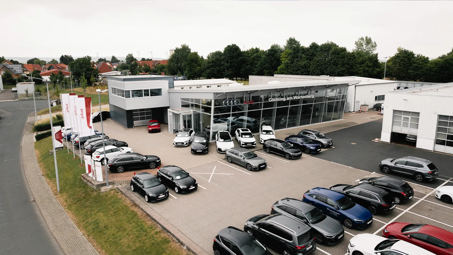 Eine Aufnahme des Audi Autohauses in Eisenach, dass das Gebäude und Audi Fahrzeuge vor dem Gebäude, sowie die Einfahrt zeigt.
