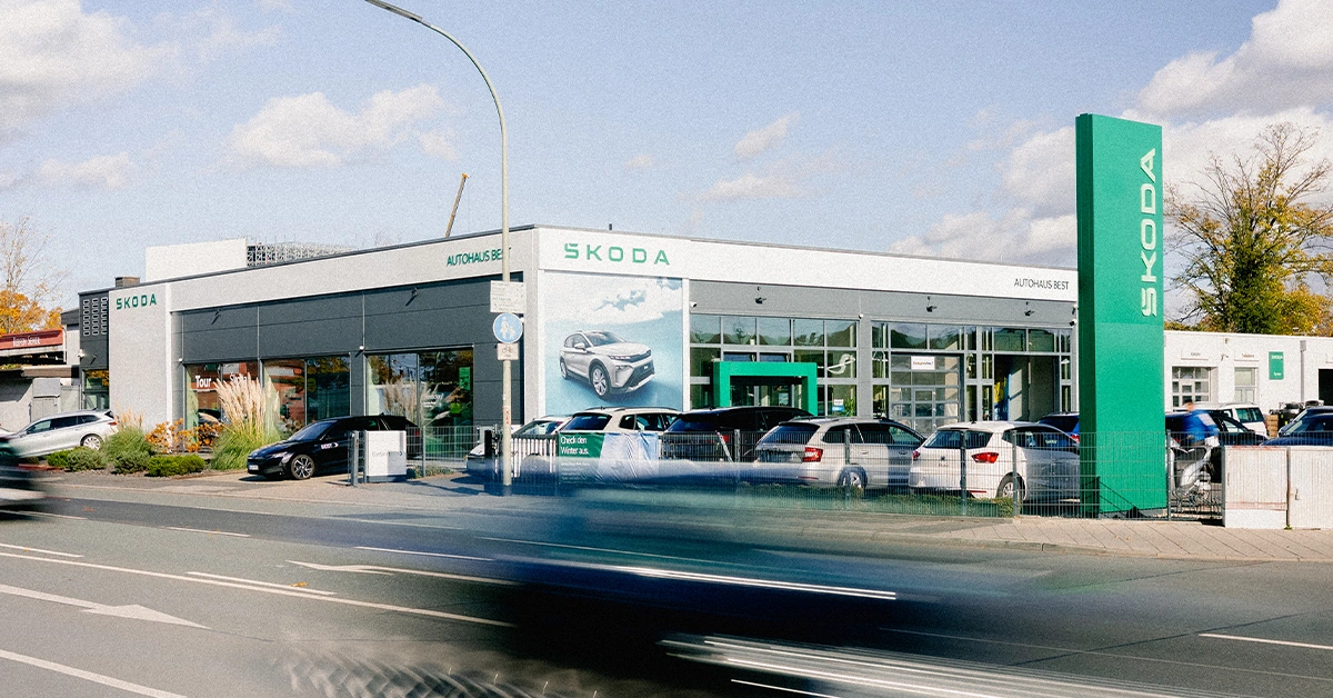 Eine Aufnahme des Škoda Autohauses in Offenbach am Main, die das Gebäude und Škoda Fahrzeuge vor dem Gebäude, sowie die Einfahrt zeigt.