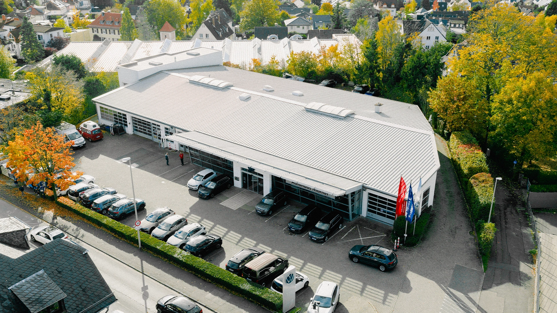 Eine Aufnahme des Volkswagen Autohauses in Königstein im Taunus, dass die Gebäude und Volkswagen Fahrzeuge vor dem Gebäude, sowie die Einfahrt zeigt.