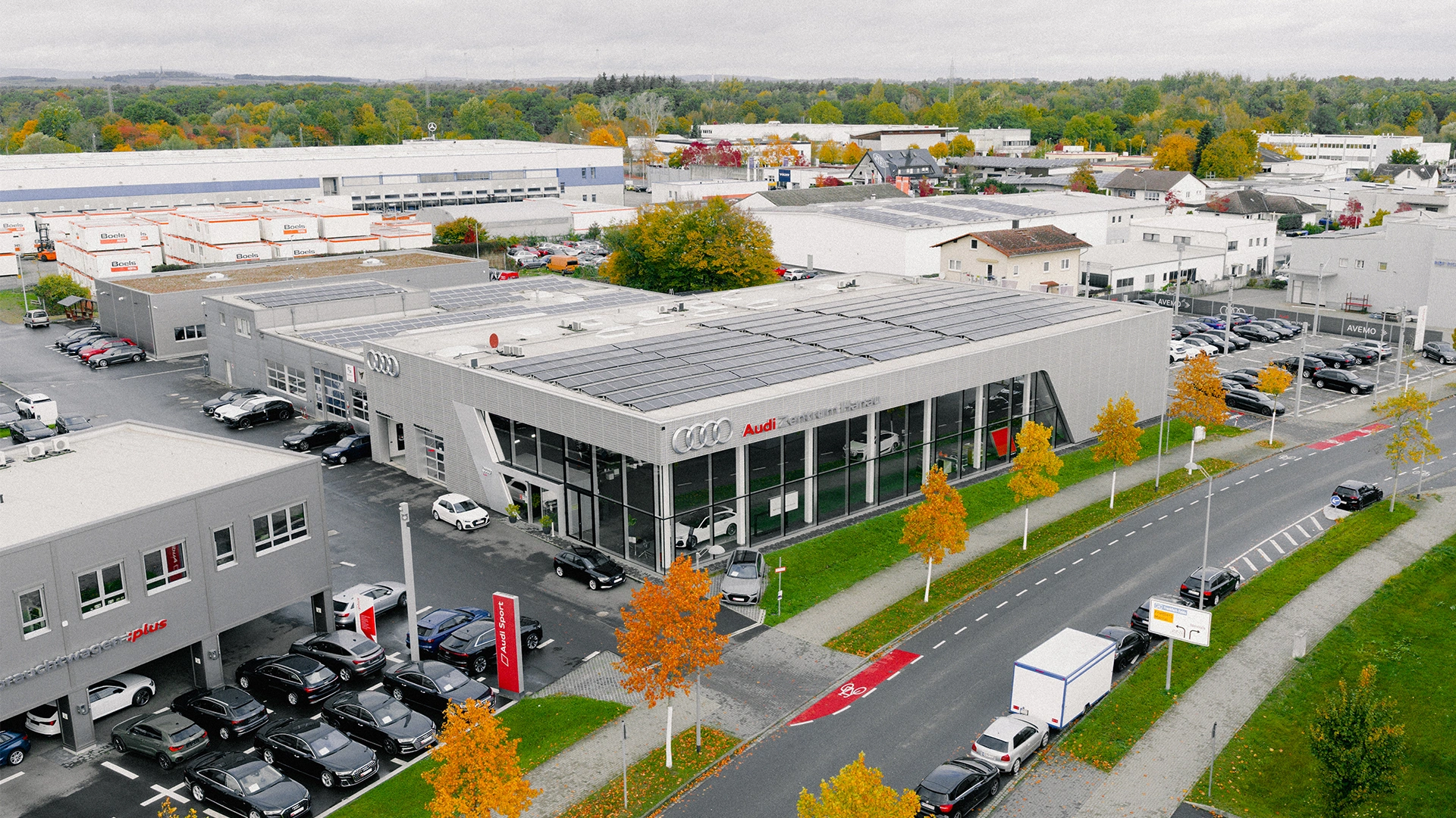 Audi Zentrum Hanau Header Eine Aufnahme des Audi Zentrum Autohauses in Hanau, dass die Gebäude und Audi Fahrzeuge vor dem Gebäude, sowie die Einfahrt zeigt.