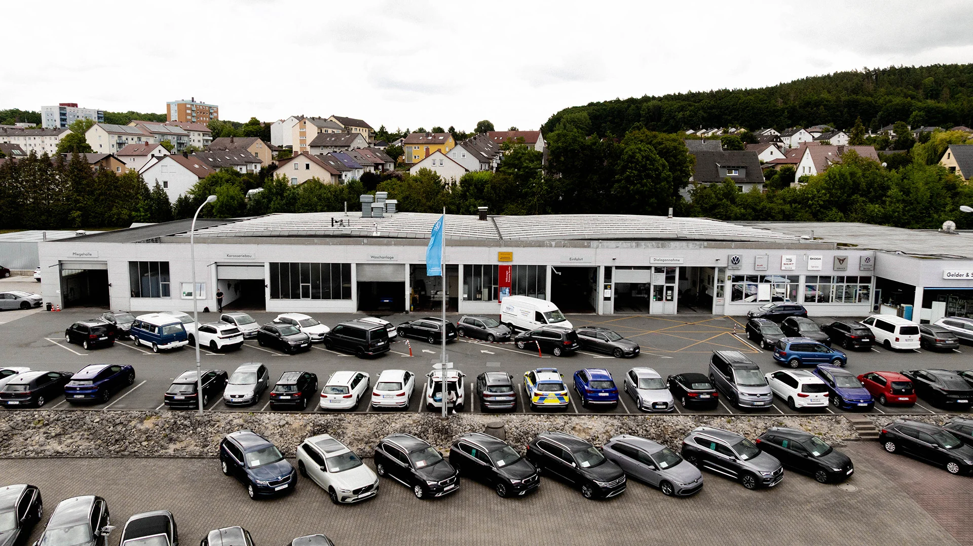 Luftaufnahme des AVEMO Autohauses in Lichtenfels mit einem großen Gebrauchtwagenhof, auf dem zahlreiche Volkswagen vor dem Werkstattgebäude geparkt sind.