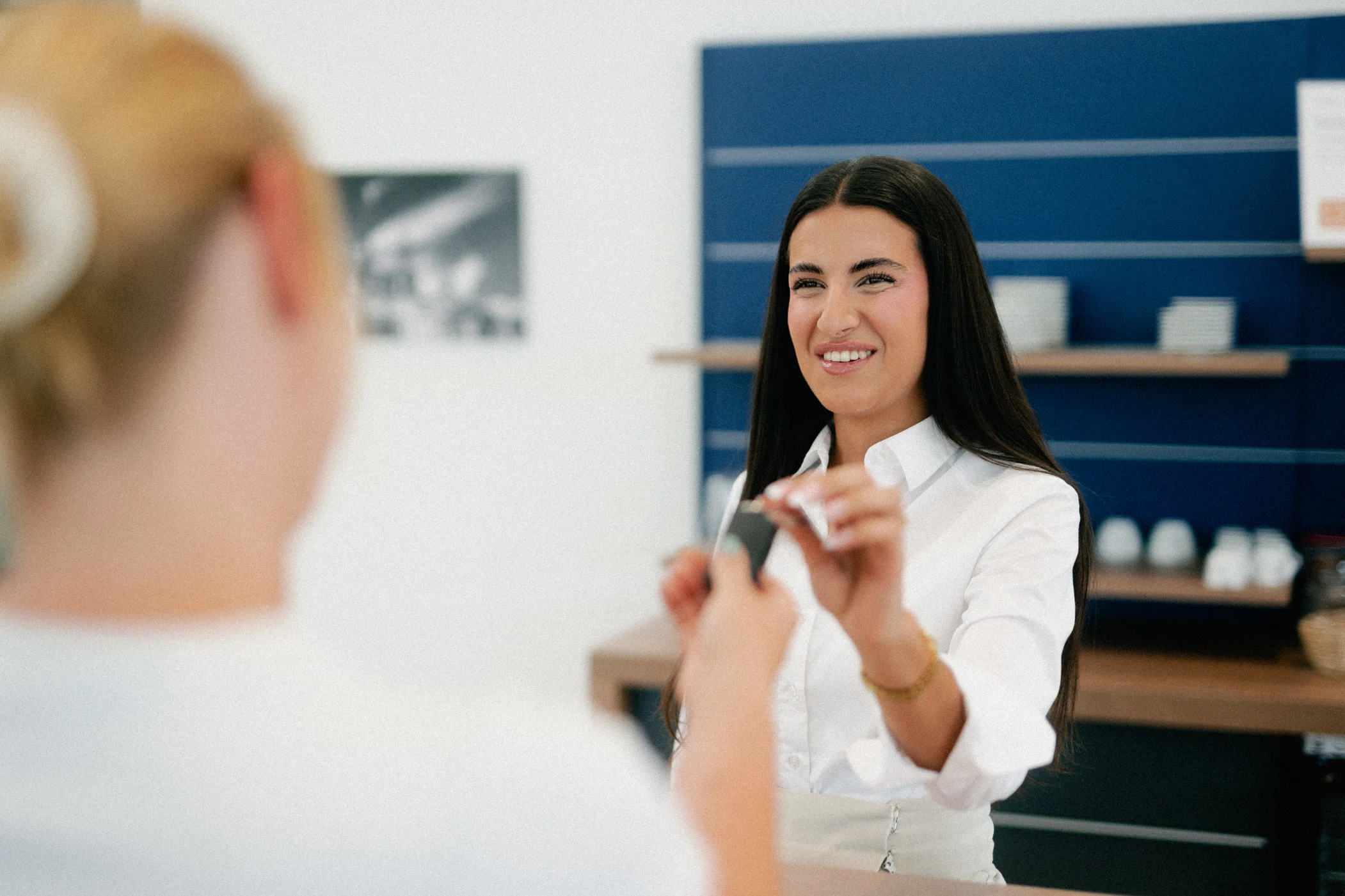 Information Schlüsselübergabe w,w Zu sehen ist eine Service-Mitarbeiterin, die einer Kundin einen Autoschlüssel aushändigt.
