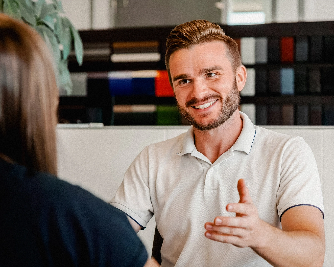Eine Aufnahme eines lachenden Verkaufsberaters, der sich mit einer Frau unterhält und dabei gestikuliert.