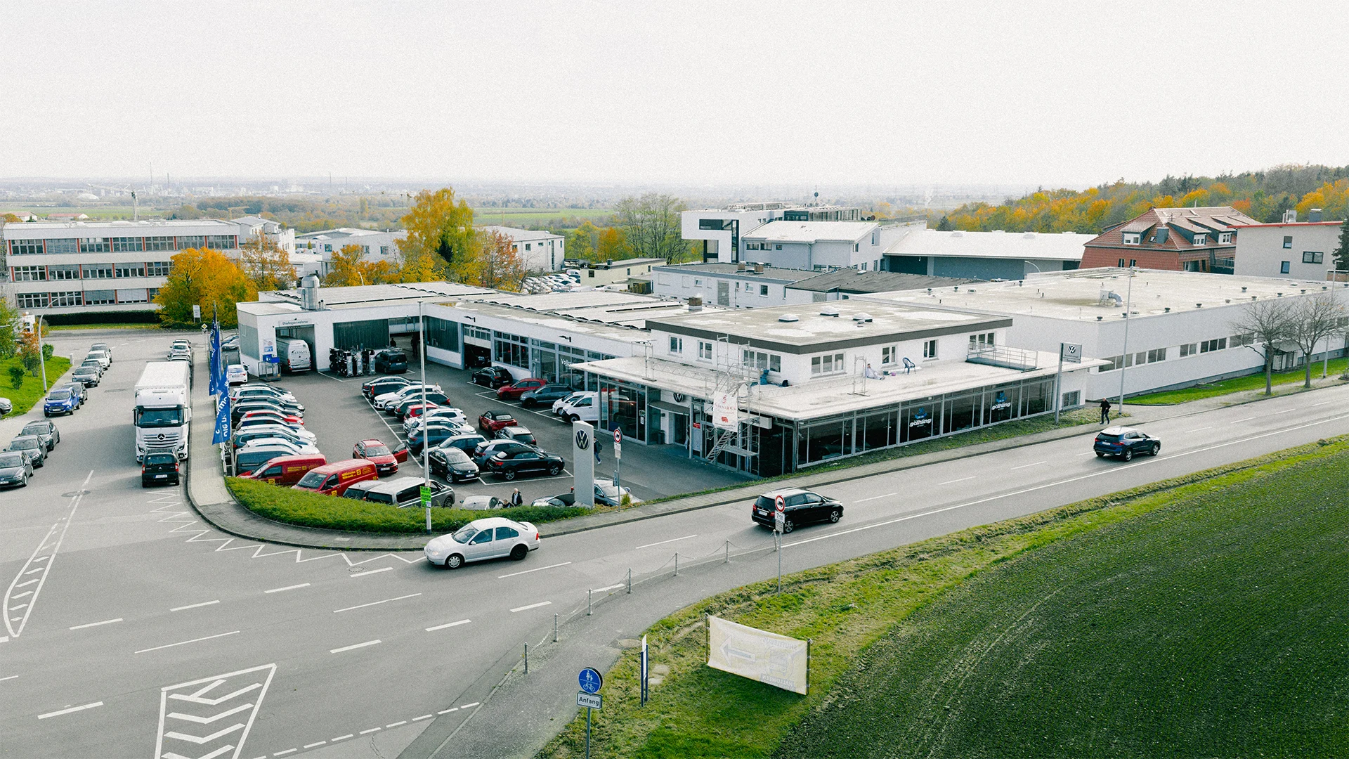 Eine Aufnahme des Volkswagen Autohauses in Kelkheim, dass die Gebäude und Volkswagen Fahrzeuge vor dem Gebäude, sowie Parkplätze und die Dieselstraße zeigt.