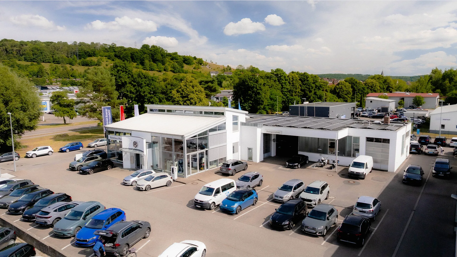 Eine Aufnahme des Volkswagen Autohauses in Heidenheim, dass das Gebäude und Volkswagen Fahrzeuge vor dem Gebäude, sowie den Parkplatz zeigt.