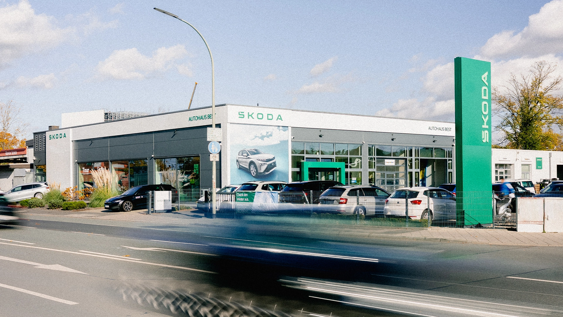 Škoda Offenbach Header Eine Aufnahme des Škoda Autohauses in Offenbach am Main, dass das Gebäude und Škoda Fahrzeuge vor dem Gebäude, sowie die Einfahrt zeigt.
