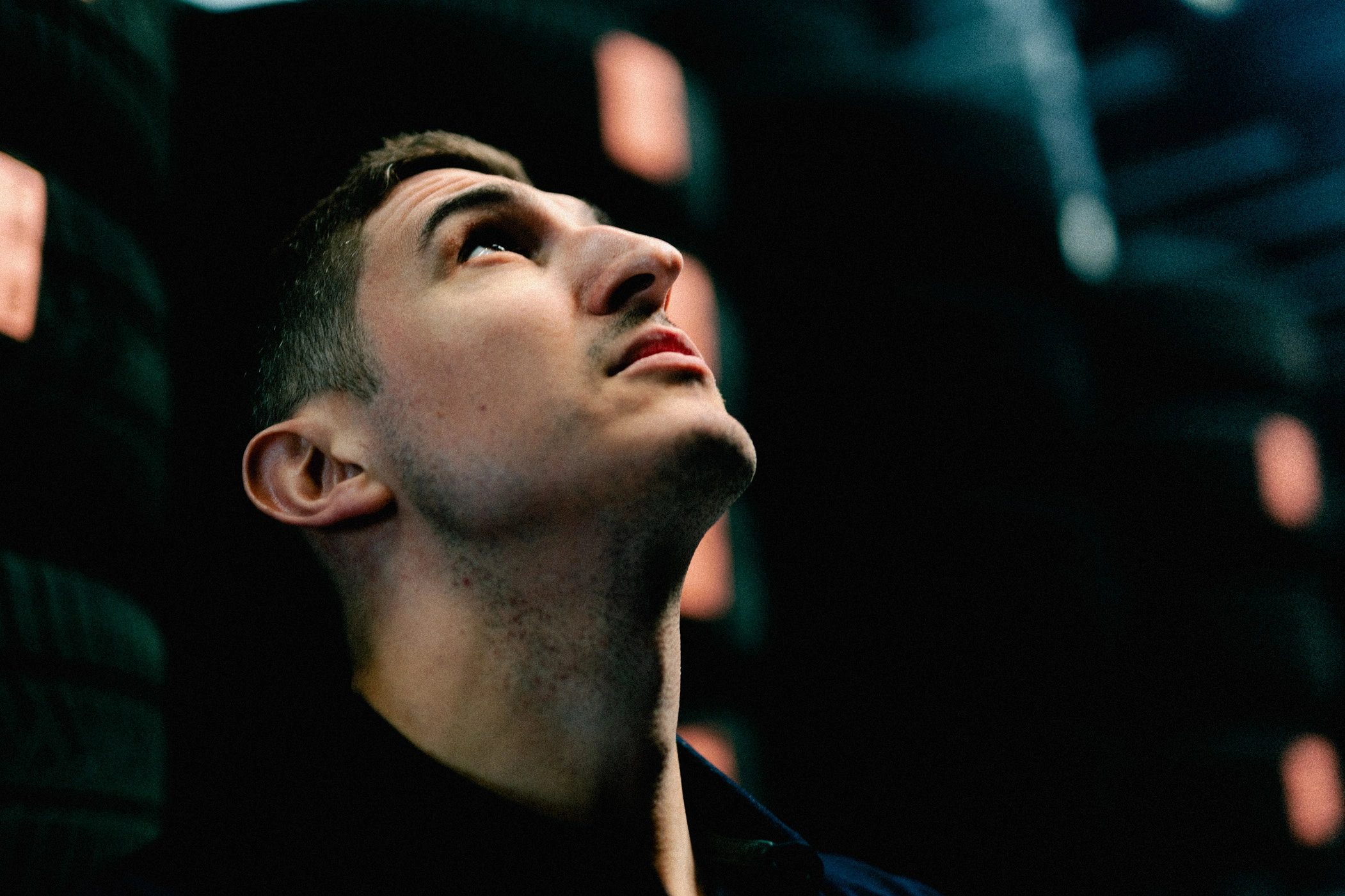 Zu sehen ist das Gesicht eines Teiledienst-Mitarbeiters, der im Reifenlager steht und nach oben schaut, um nach etwas im Regal zu suchen.