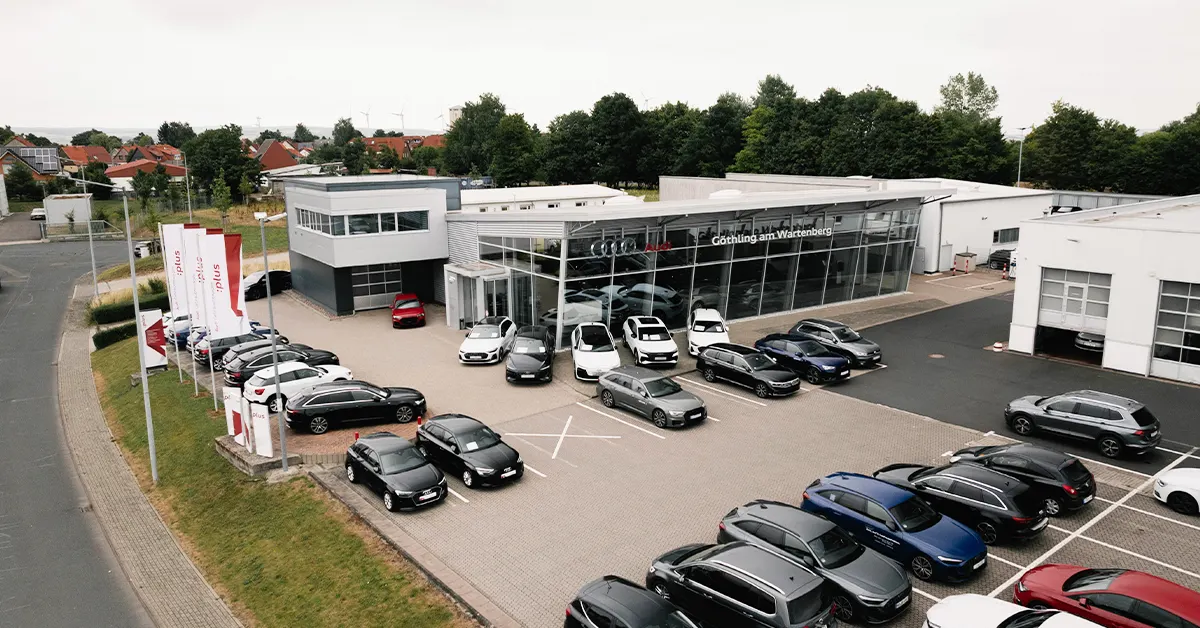 Eine Aufnahme des Audi Autohauses in Eisenach, die das Gebäude und Audi Fahrzeuge vor dem Gebäude, sowie die Einfahrt zeigt.