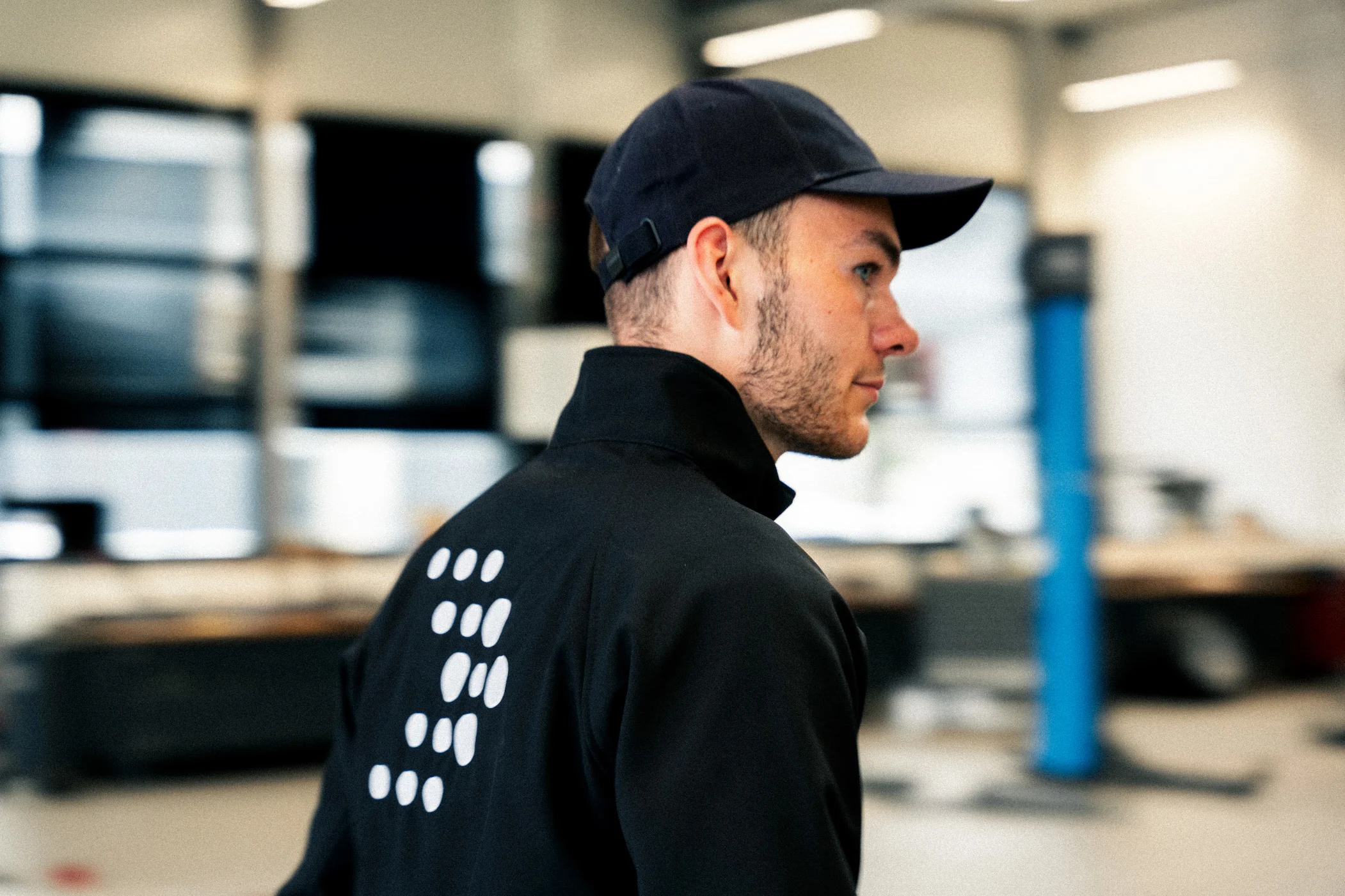 Werkstatt laufen m Ein Mann mit schwarzer AVEMO-Jacke und einer Kappe läuft durch die Werkstatt des Autohauses.