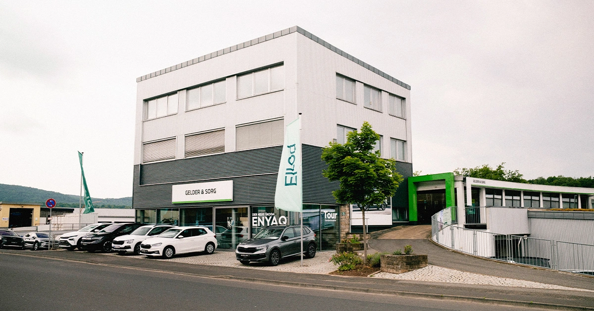 Eine Aufnahme des Škoda Autohauses in Bad Kissingen, die das Gebäude und Škoda Fahrzeuge vor dem Gebäude, sowie die Würzburger Straße zeigt.