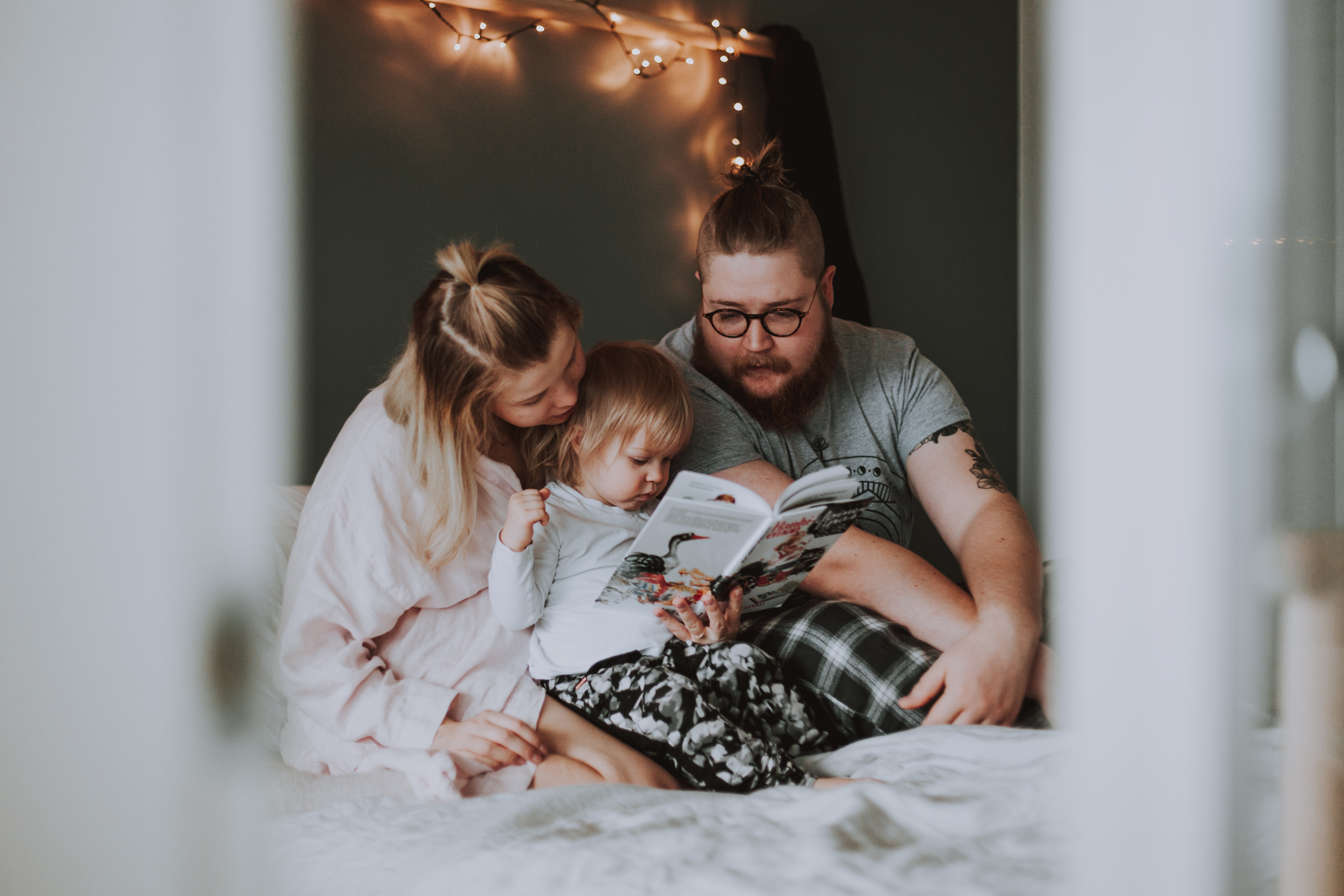 Pehekuvaus tai perhepotretit kotona, jossa vanhemmat lukee lapselle kirjaa