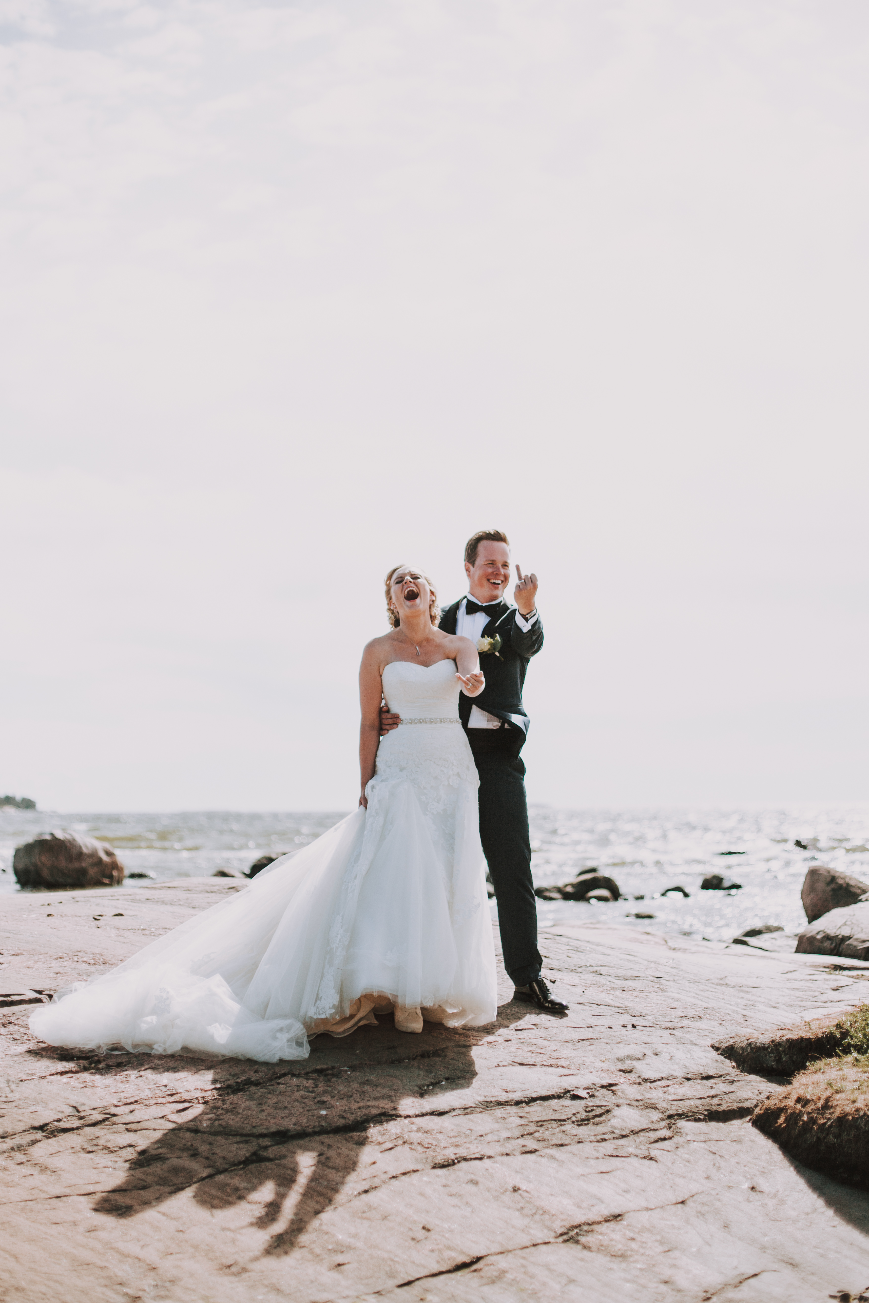 Hääpari Lauttasaaressa merenrannassa poseeraamassa nauraen hääpotrettien aikana