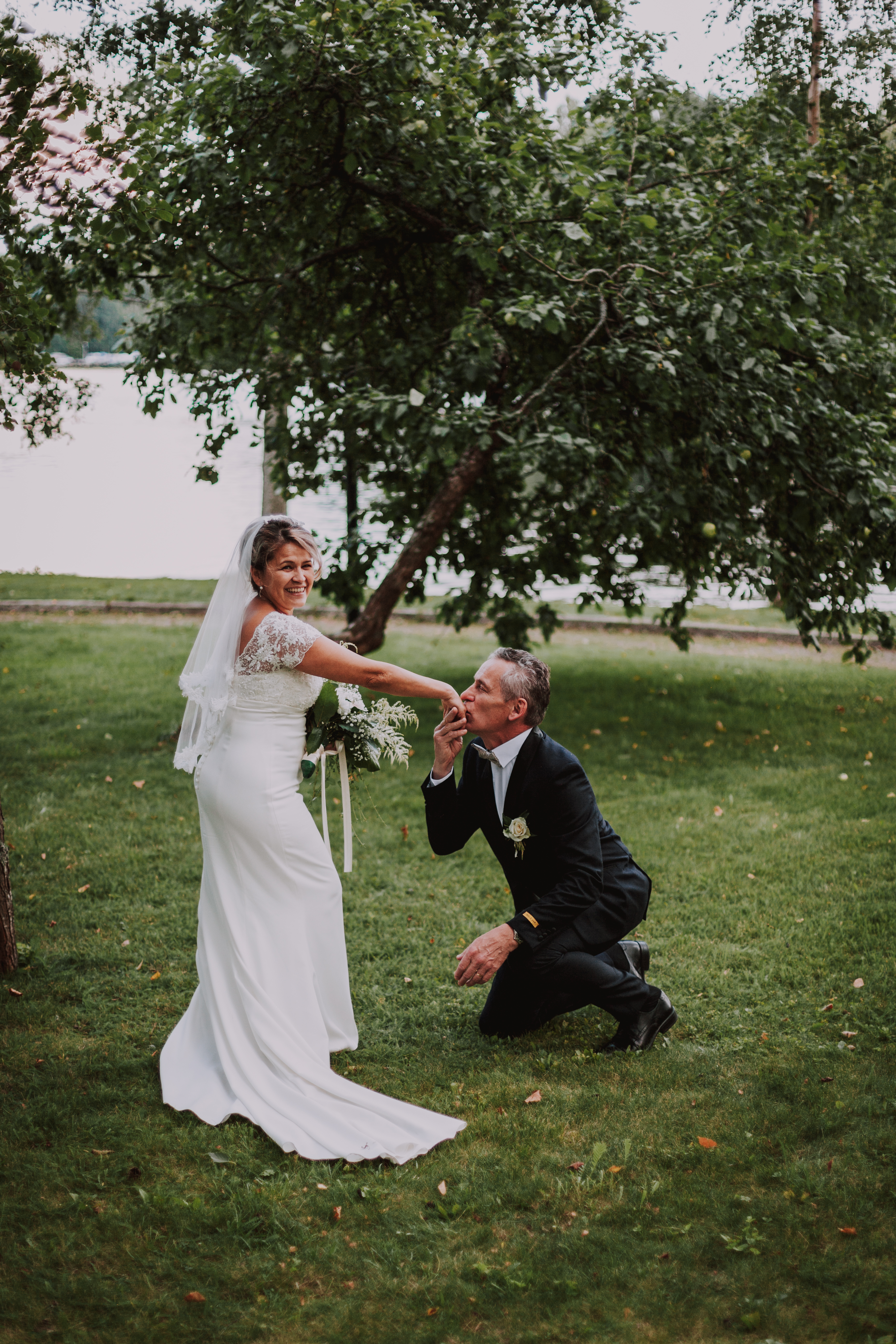 Sulhanen polvistunut nauravan morsiamen eteen hääkuvauksessa Heinolassa