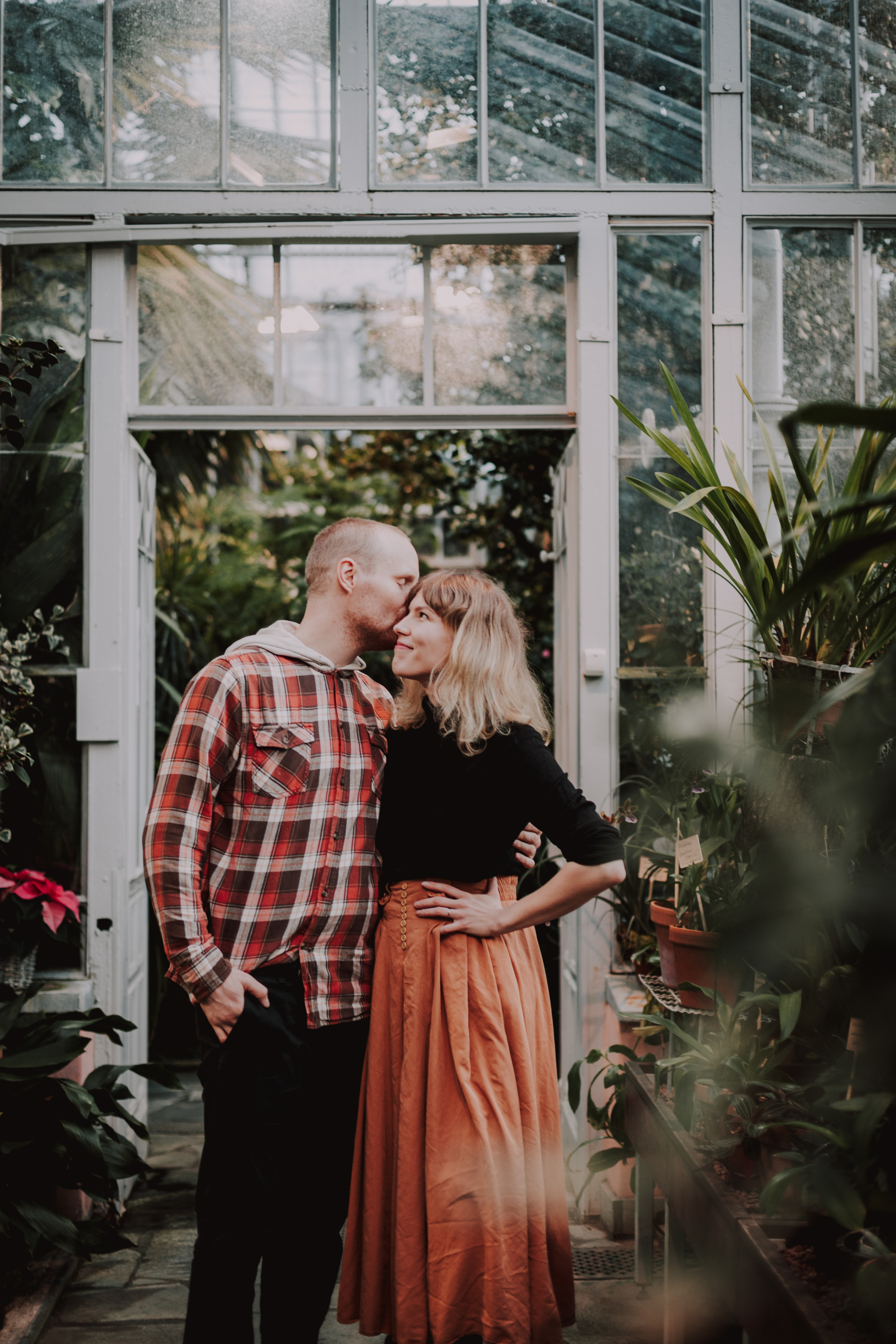 Pari parikuvauksessa Talvipuutarhassa Helsingissä. Mies antaa suukon naisen poskelle.