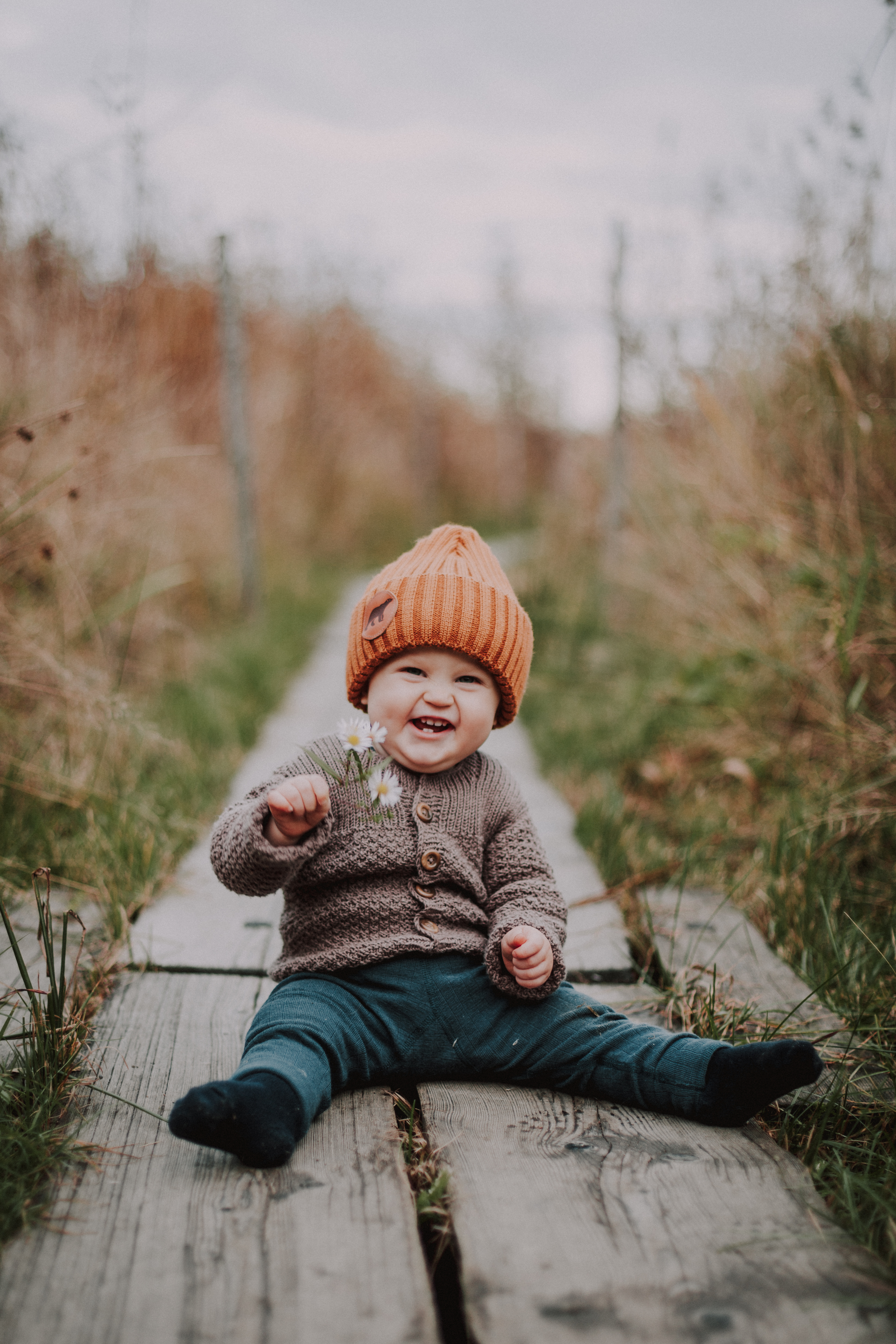 1-vuotiskuvauksessa vauva nauraa kukka kädessä Lammassaaressa, Helsingissä