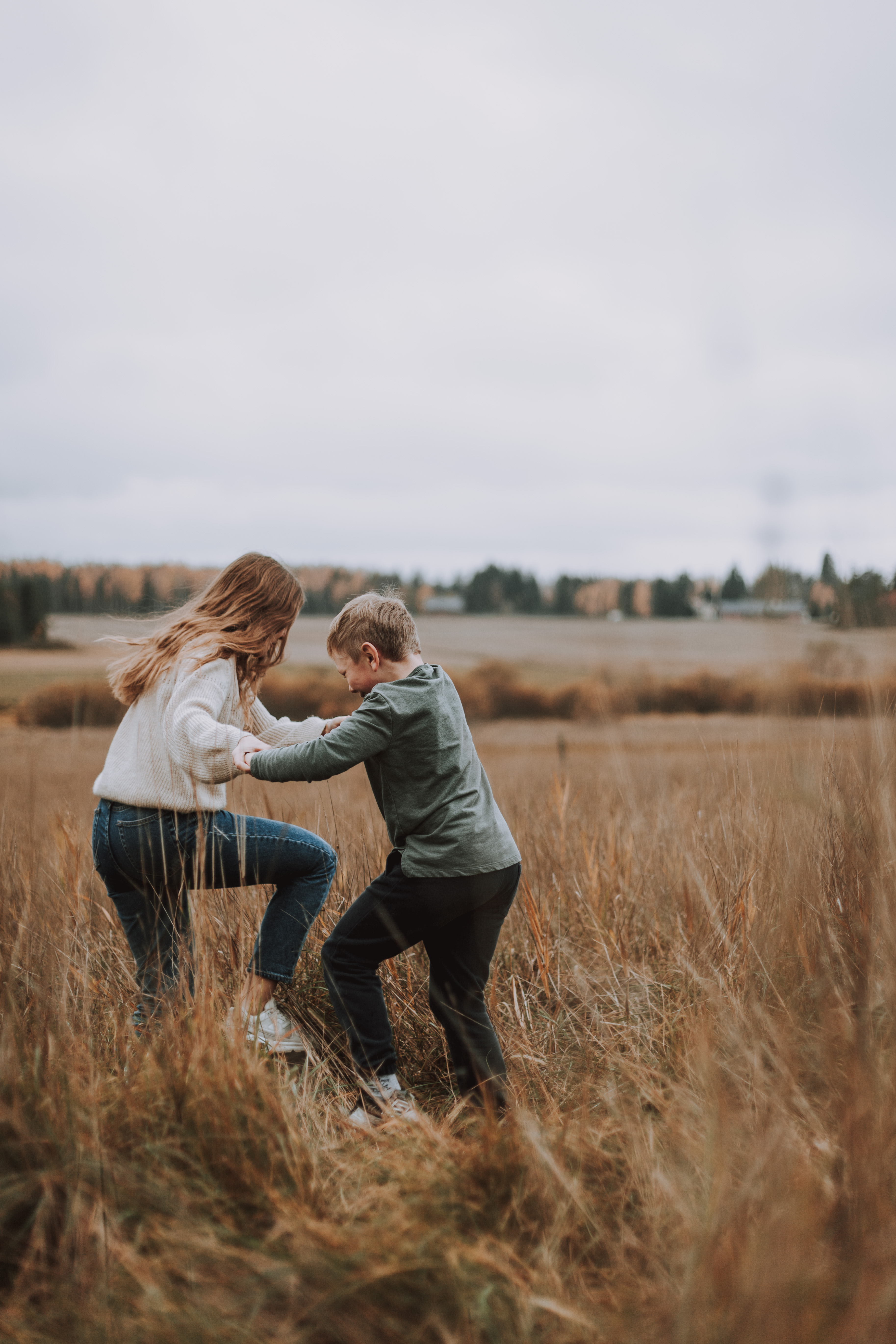 Tyttö ja poika tanssivat miljöökuvauksessa pellolla