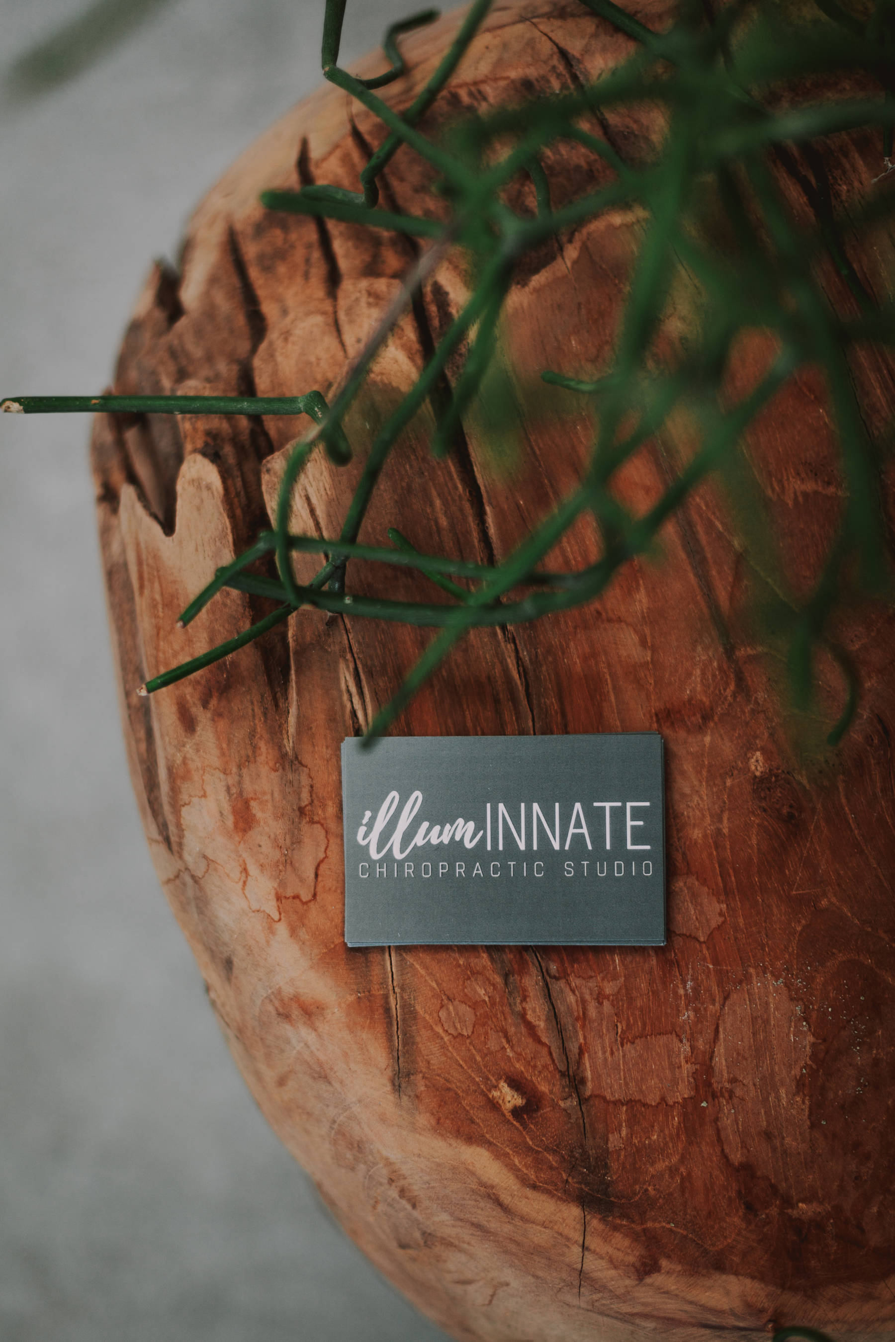 IllumINNATE Chiropractic studio's business cards on a wooden table in a brand photoshoot