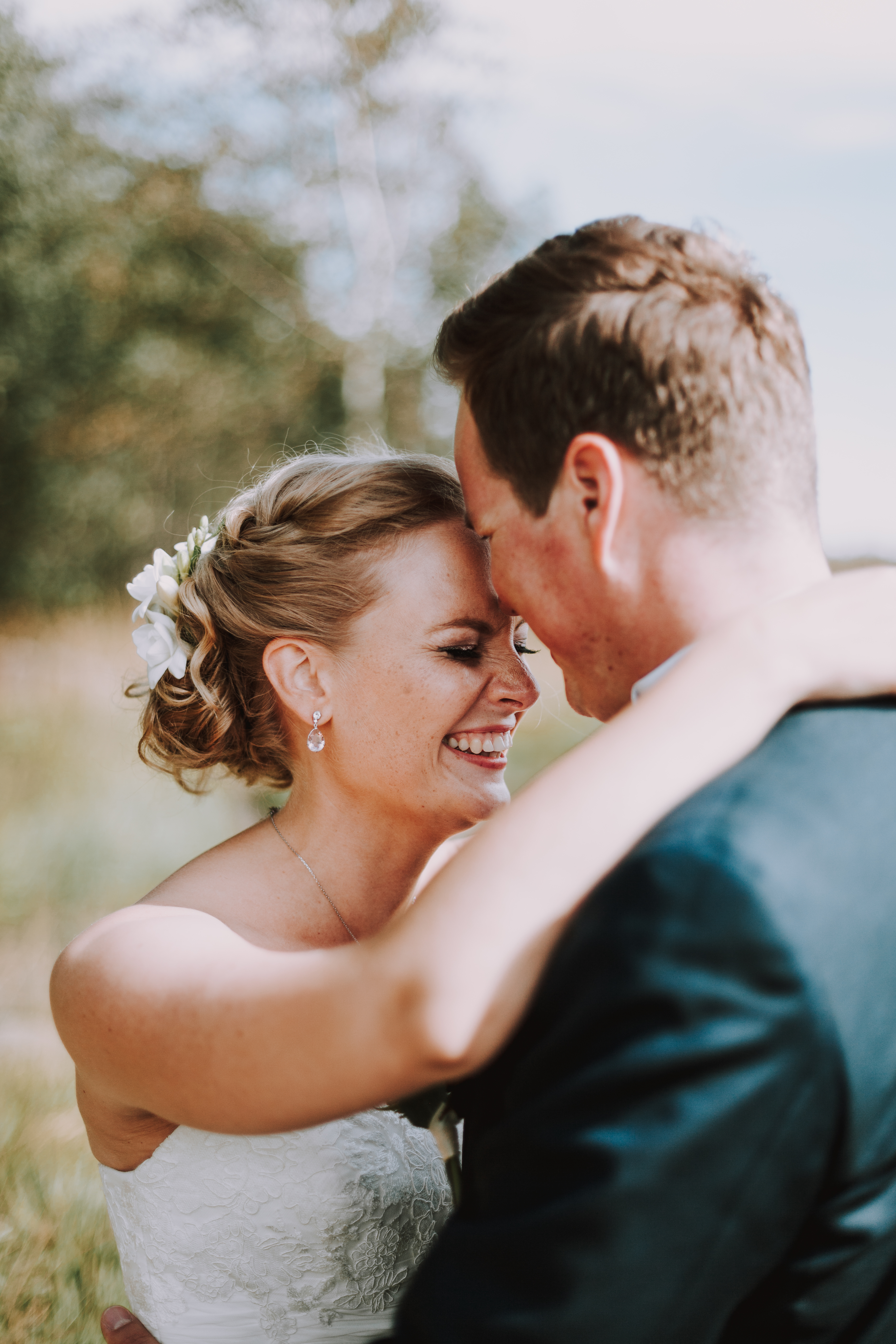 Hääpotrettikuvauksen lähikuva hymyilevästä hääparista Lauttasaaren rannassa Helsingissä