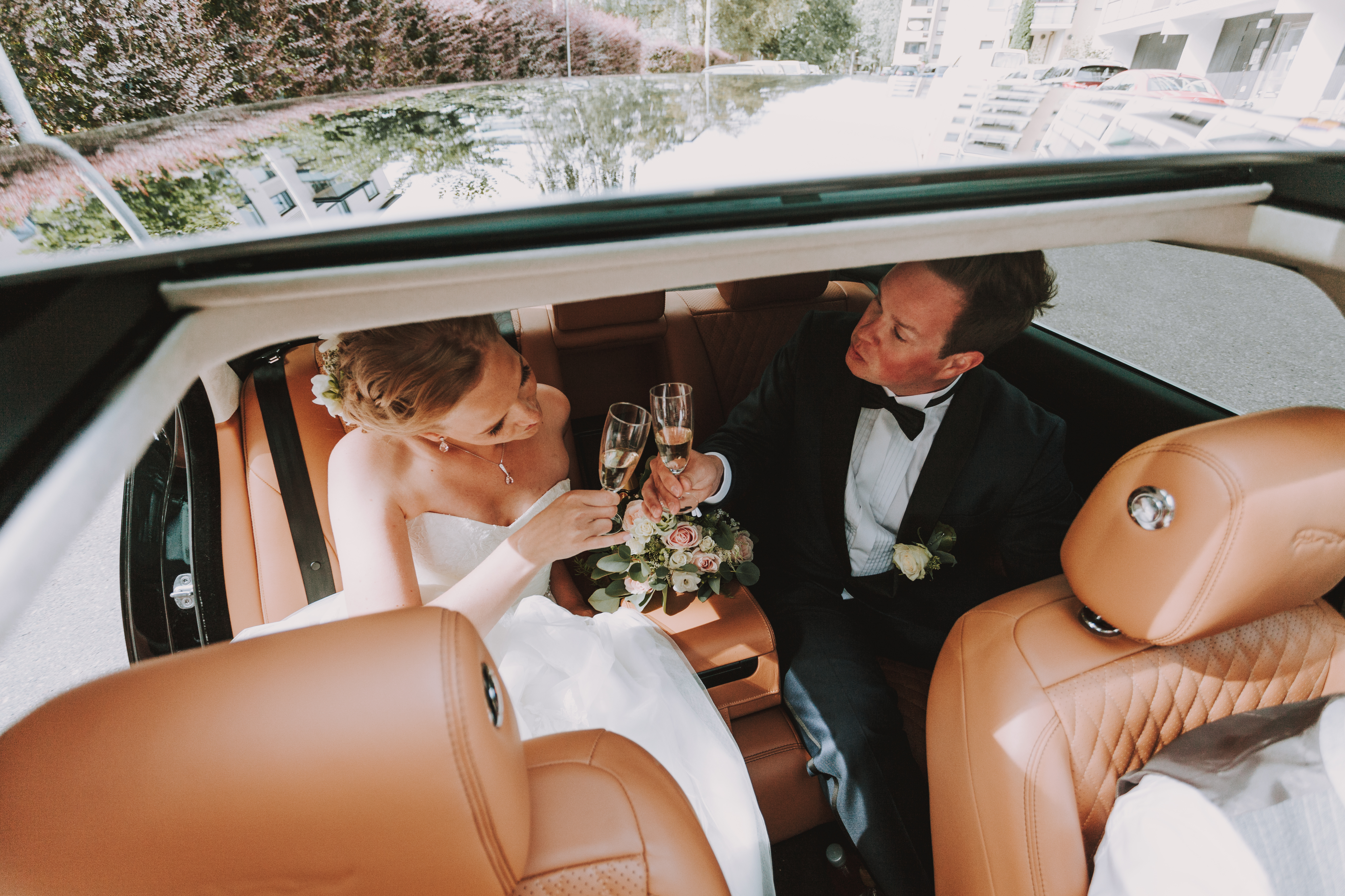 Hääpari kilistelee maljoja hääautossa hääkuvauksen aikana