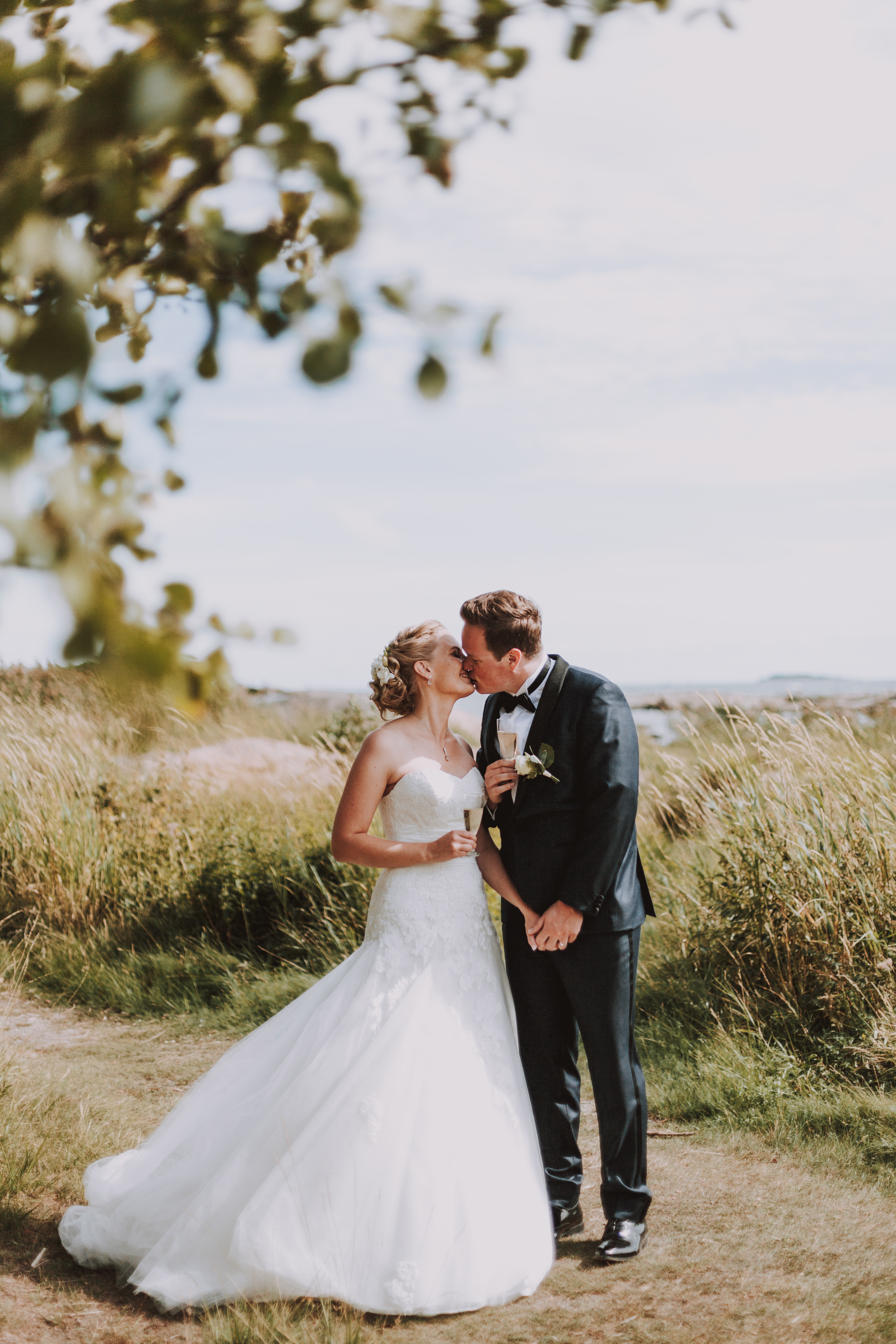 Hääpari juhlamaljat kädessä hääkuvauksessa Lauttasaaressa Helsingissä hääpotrettien aikana