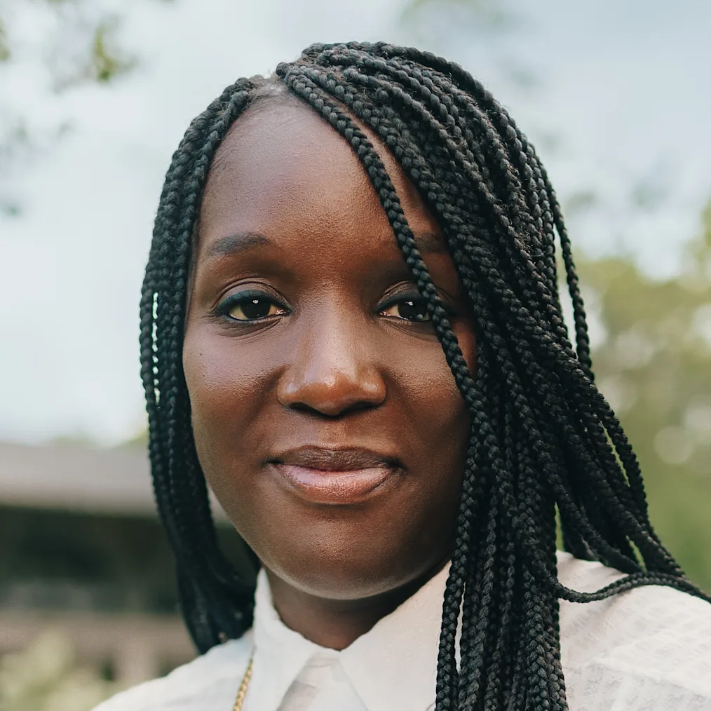 A Black woman with braids and a confident smile