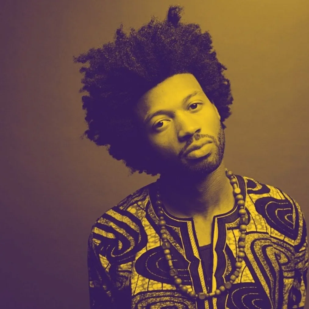 A portrait with a duotone yellow overlay of Sam Thousand, a Black man with a medium-dark skin tone, a trimmed facial hair. His head tilts slightly as he looks forward. He has a voluminous, textured afro and wears a patterned dashiki shirt with a long beaded necklace.
