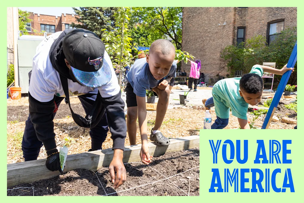 An adult and 2 children planting seeds in a garden
