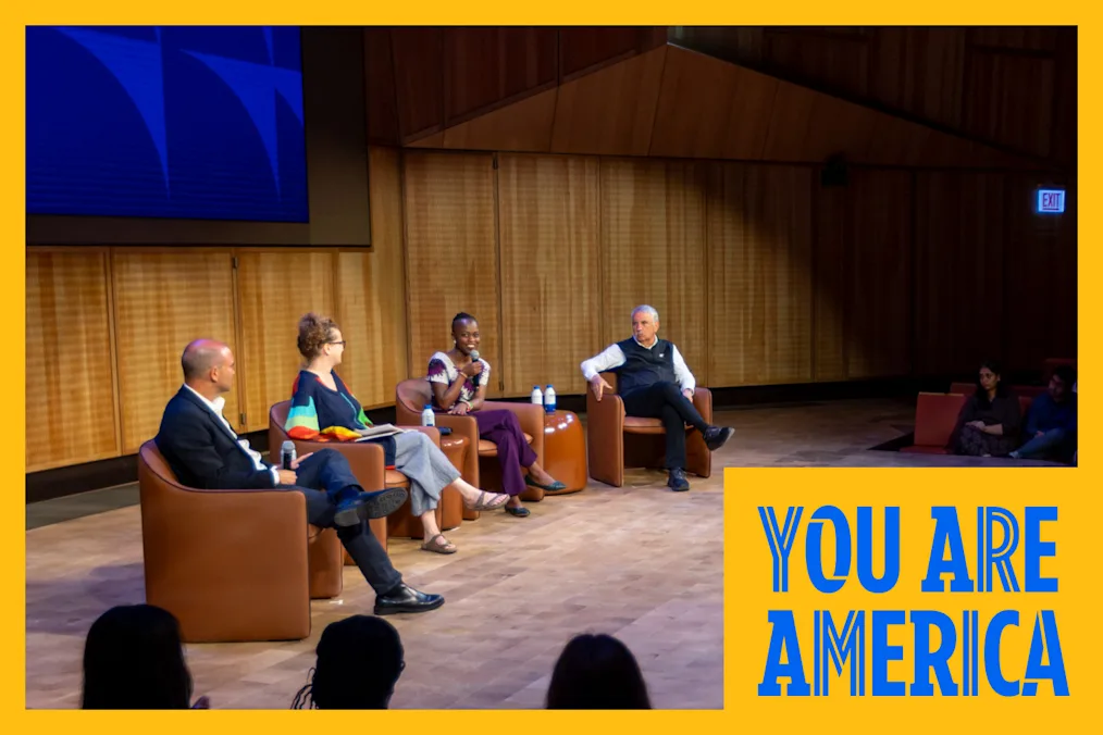 4 people sit in chairs on the stage of the auditorium