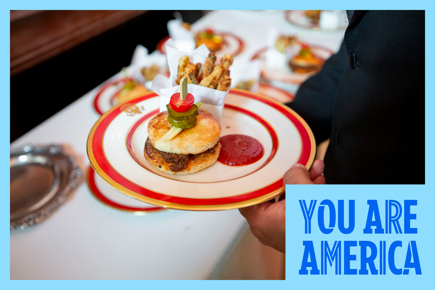 A plated slider with fries is served at a table, highlighting a small bite from a culinary event.