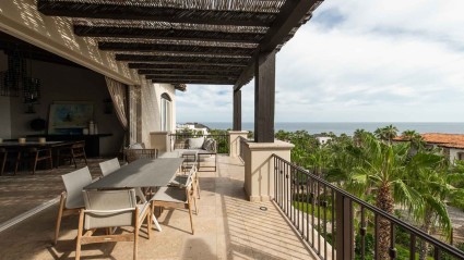 A scenic ocean view from a Canvo vacation home balcony with tables and chairs