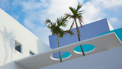 A minimalist Miami architectural scene with pristine white walls, geometric forms, and palm trees set against a vivid blue sky, perfectly embodying the essence of understated luxury and contemporary elegance.