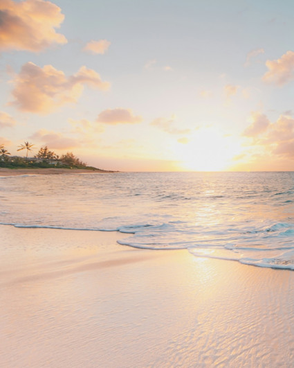 View of white sand beach with turquoise water with the sun setting.
