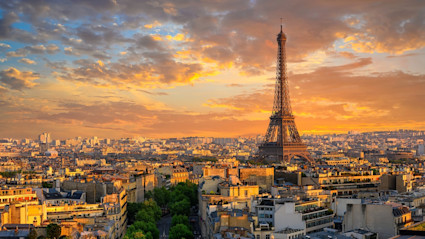 An iconic panoramic view of Paris with the Eiffel Tower, bathed in sunset hues, symbolizing global luxury and the international lifestyle of the modern homeowner. The warm, aspirational cityscape captures the allure of living and thriving in sought-after world cities.