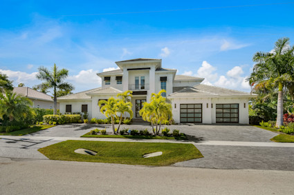 front view of a Marco Island home with manicured landscaping and a spacious driveway, embodying the relaxed coastal community atmosphere that welcomes visitors and residents as farmers market season returns