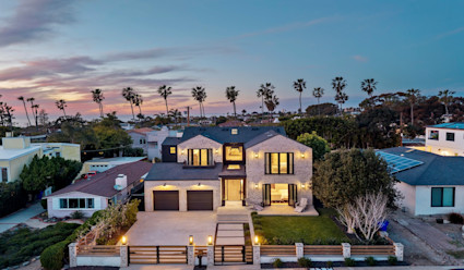 Front exterior of Westbourne illuminated at night with the surrounding neighborhood and coast in the background.
