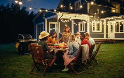 Friends enjoy a dinner party under a canopy of lights at a luxury vacation home.