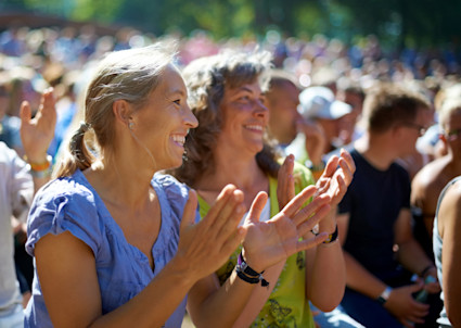 Women in the audience at a concert applauding.
