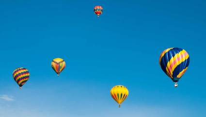 Five hot air balloons float in the sky, one of the top Steamboat Springs summer activities.