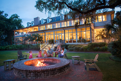 A family gathered around a fire pit outside their vacation home in Lowcountry, enjoying a cozy evening together