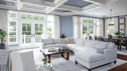 Before-and-after transformation of the Surfsong living room, shifting from soft blue walls and a casual layout to a bright, refined coastal design.Before-and-after transformation of the Surfsong living room, shifting from soft blue walls and a casual layout to a bright, refined coastal design.